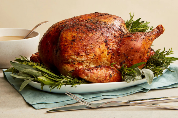 A delicious roasted turkey with herbs on a plate, paired with a cup of aromatic coffee.