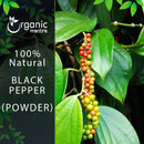 Organic Mantra 100% natural Black Pepper Powder product image capturing a live pepper vine with a cluster of ripening peppercorns transitioning from green to red against broad tropical leaves.