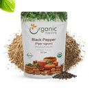 Organic Mantra Black Pepper (Piper nigrum) Powder, 227g resealable bag with USDA Organic and OneCert certifications, origin India, is presented against a generous mound of ground pepper and whole peppercorns.