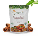 Organic Mantra Cinnamon Cassia Cinnamomum cassia Sticks 227g white resealable standing pouch with USDA Organic and OneCert Organic certifications and India origin label, centered on a white background flanked by thick rolled cassia bark sticks on both sides, a fresh green cassia branch at the top right, and a small green leaf at the bottom left.
