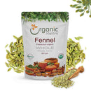 Organic Mantra Fennel (Foeniculum vulgare) Whole 227g white resealable pouch with USDA Organic and OneCert Organic certifications and India origin label, flanked by loose green-striped fennel seeds, a wooden scoop, and a fresh fennel umbel flower cluster.