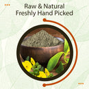 Raw and natural, freshly hand-picked Gokshura powder heaped in a dark rustic wooden bowl with bright yellow Tribulus terrestris flowers, spiky raw Gokshura seed pods, and a large fresh green leaf arranged in front, framed inside a dark olive-brown double circle with a rust-orange decorative arc over a cream leaf-vein texture background.