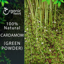 Organic Mantra 100% natural Green Cardamom Powder product image showing a dense field of tall cardamom plant stems with small green pods and tiny pink flowers growing at the base.