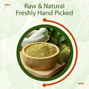 Raw, freshly hand-picked Neem Leaf Powder in a round wooden bowl on a wooden board, with a white mortar and pestle and fresh whole neem leaves visible in the background.