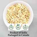 Top-down view of a round white ceramic bowl filled with pale cream-yellow cut and sifted Shatavari Asparagus racemosus root pieces on a light grey background, displaying three green circular badges for Vegan, 100% Organic, and Gluten-Free certifications, captioned "Product of India. "Packaged in Canada."